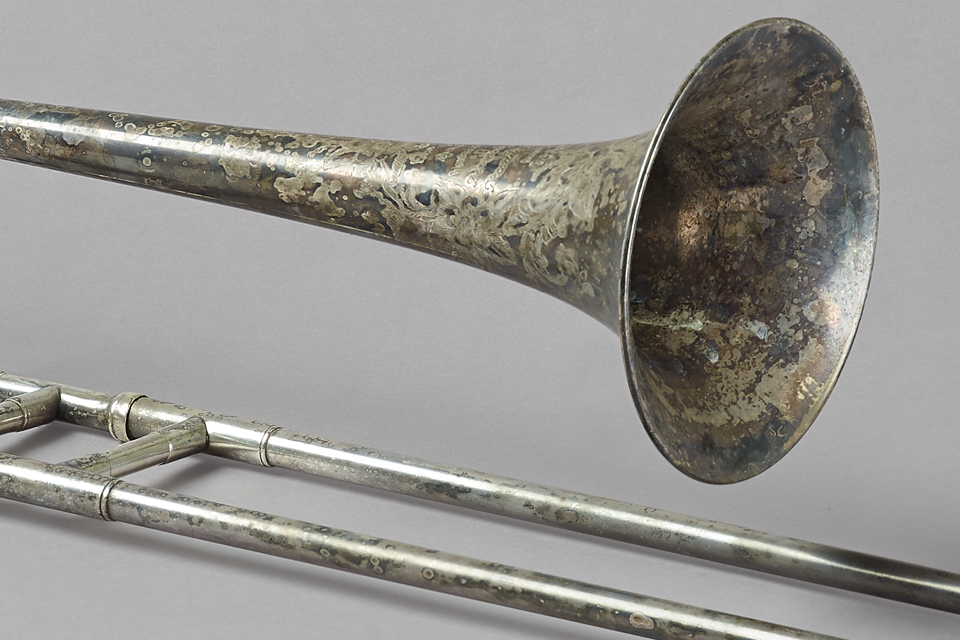 An image of Gustav Holst's intricately decorative Trombone behind a grey background.